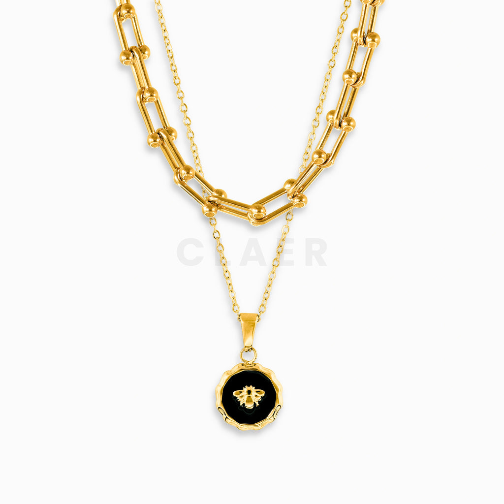 Goldene Horseshoe-Kette mit Bienen-Charm-Kette im Layering-Look.