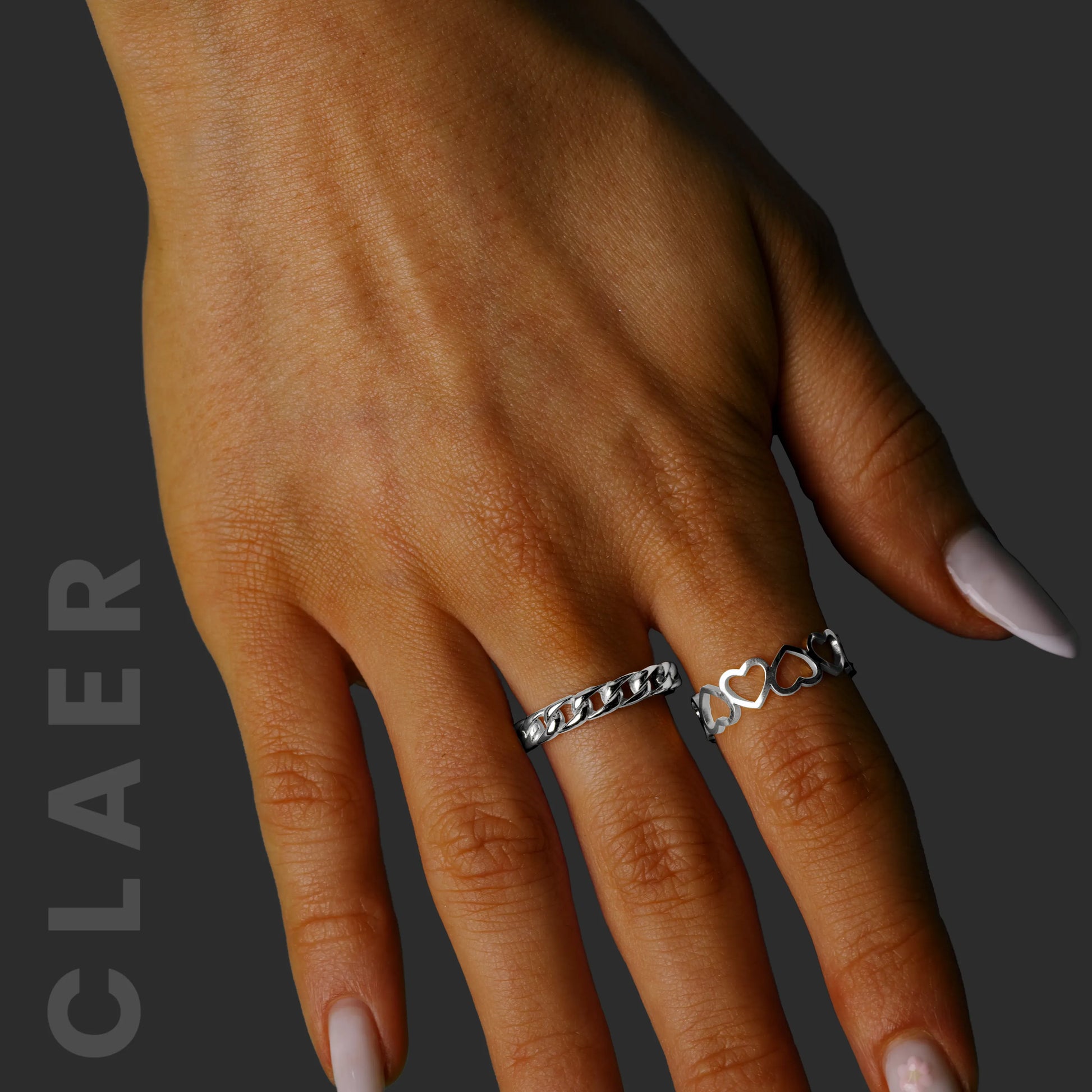 Silberner Cuban-Ring und ein Ring mit Herzmotiven.