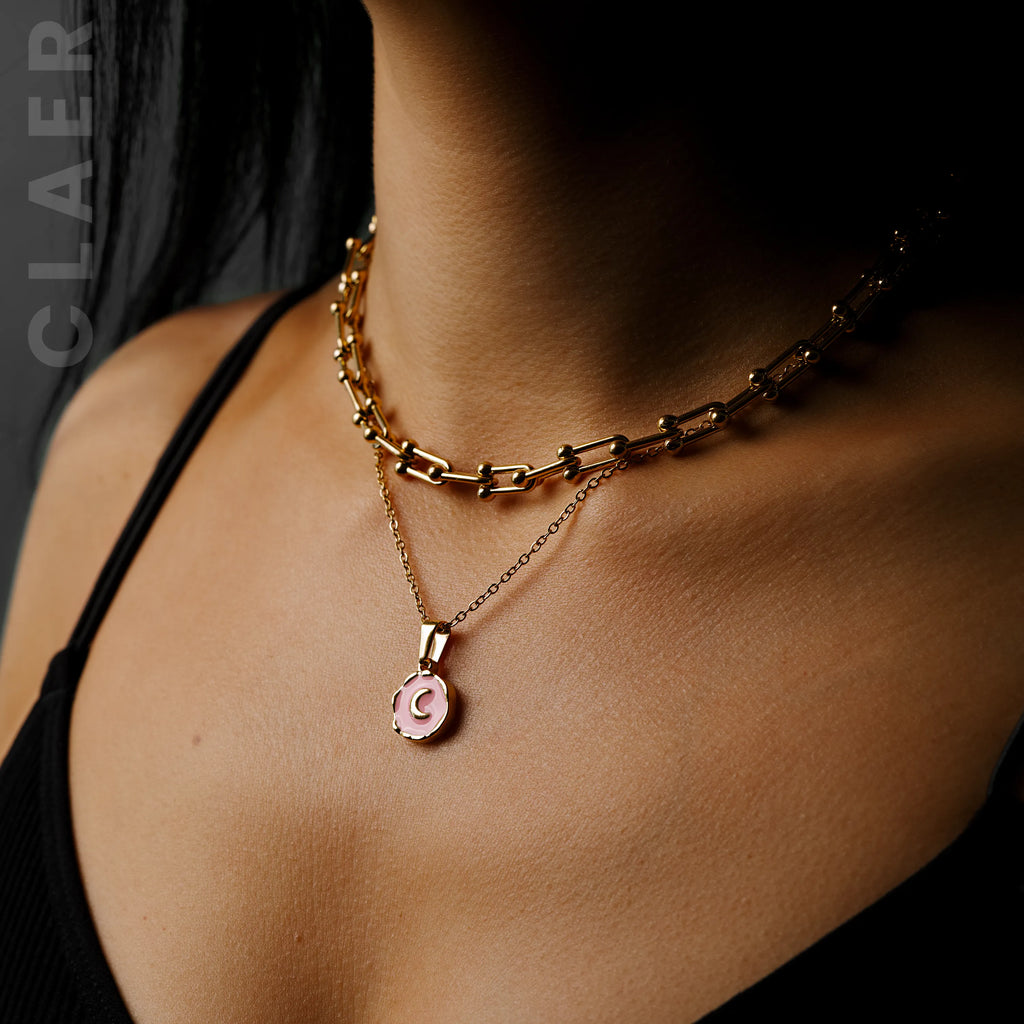Goldene Horseshoe-Halskette und Gliederkette mit einem Mond-Charm, getragen.